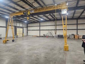 5-ton motorized gantry crane with electric hoist, powered travel drive, and festooned pendant controls installed in an industrial facility.